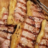 Cortes de carne marcados a la parrilla sobre tabla de madera
